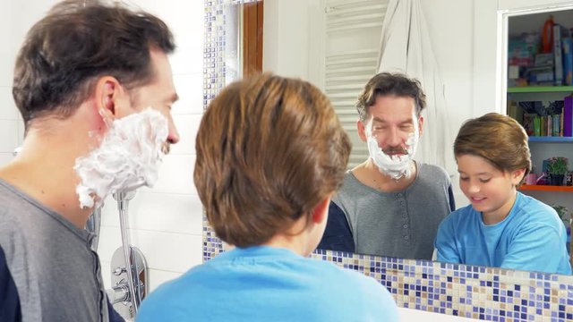 Kid laughing applying shaving cream to dad
