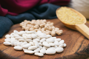 Dry Beans, Chickpeas And Wooden Spoon Full of Cracked Wheat On A Wooden Surface