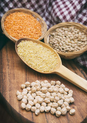 Vertical Shot Of Chickpeas, Red And Green Lentils And A Wooden Scoop Full Of Cracked Wheat