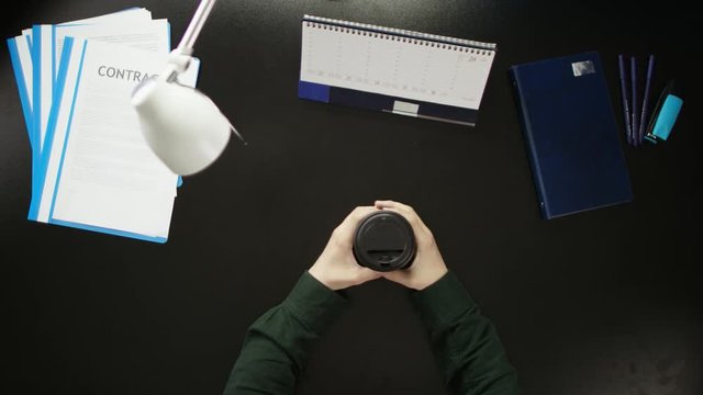 A man is sitting at an office desk and using a phone.