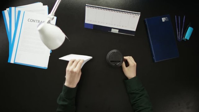 A man is sitting at an office desk and using a phone.