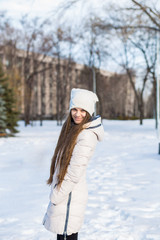 Fototapeta na wymiar Portrait of a beautiful girl in white with very long hair in a snowy winter. Winter lifestyle portrait of beautiful girl walking in the snowy park
