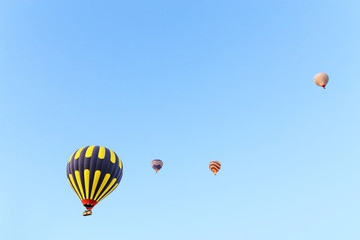 Many unrecognizable colorful hot air balloons against blue sky