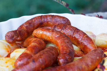 Fototapeta premium Grilled sausages with roasted potatoes in casserole dish