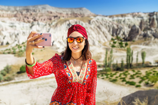 A tourist eastern asian girl makes a photo on the phone in beautiful valley in Cappadocia in Turkey.
