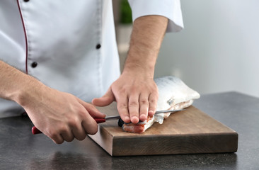 Fototapeta na wymiar Chef cutting fresh salmon in kitchen