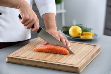 Chef cutting fresh salmon fillet in kitchen