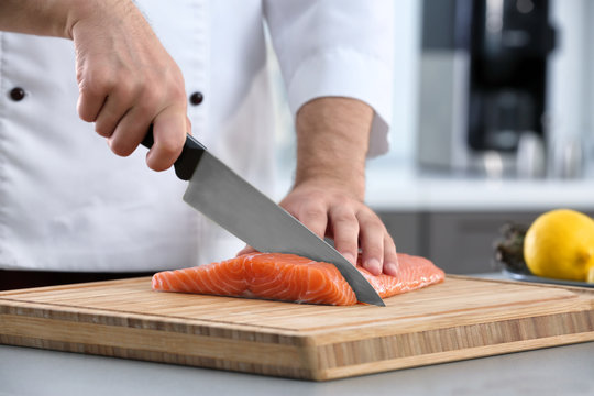 Chef Cutting Fresh Salmon Fillet In Kitchen