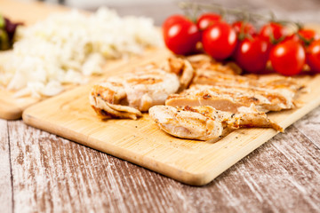Healthy diet. Fresh grilled chicken breast on wooden board next to tomatoes. Healthy dinner and lifestyle 