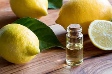A bottle of lemon essential oil with lemons