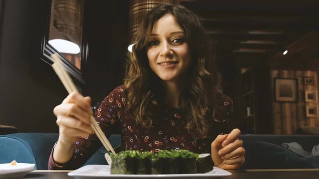 Beautiful Caucasian woman eating sushi in a Japanese restaurant, and something interesting tells his girlfriend opposite