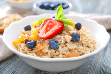Tasty oatmeal with berries in plate on table