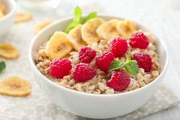 Tasty oatmeal with fruits in bowl on table