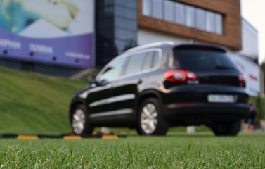 SUV parked on green parking in blur background