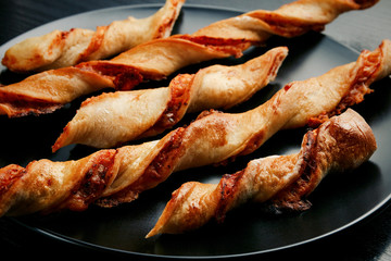Tasty appetizing cheese sticks on a black plate on a wooden black table