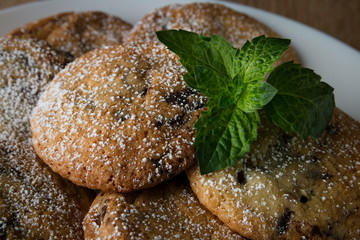 Delicious appetizing oatmeal cookies on a plate on a wooden table with a sprig of peppermint closeup