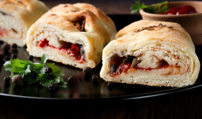 Delicious appetizing vegetarian strudels on a black plate with parsley and ketchup