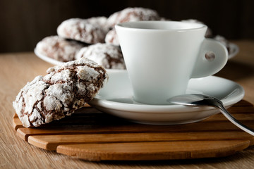 Delicious appetizing chocolate cookies cracked on a plate on a wooden table and a cup of coffee with space for text
