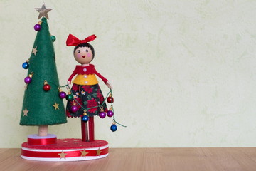 un jouet arbre de noel avec une dame qui décor avec des boules colorées,des cadeaux et bonhommes...