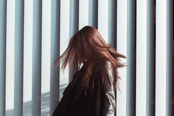 Brunette model with shiny long hair fluttering in wind, walking at the street © vpavlyuk