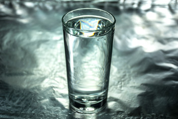 Glass of water on silver abstract background