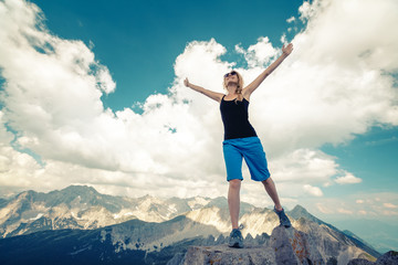 Young lady standing on top of the hill with raised hands
