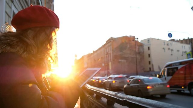 Young attractive girl with tablet in the sunset in the city. lifestyle portrait of young female using smart phone tablet for social media networking
