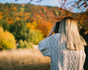girl taking shoots of nature on autumn day 