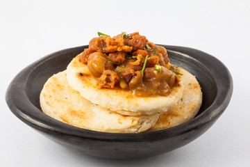 Traditional Colombian arepa topped with beans and pork rind