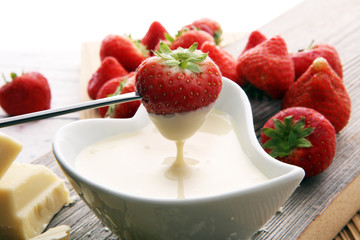 Chocolate fondue melted with fresh strawberries and white chocolate pieces.