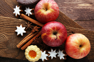 christmas cookies, apples, gingerbread and spice on brown background
