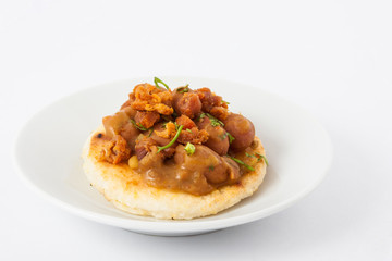 Traditional Colombian arepa topped with beans and pork rind