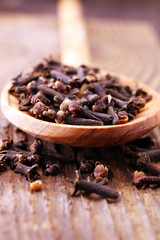 Many Dry cloves spice on brown wooden spoon.