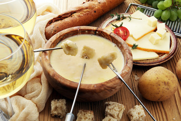 Gourmet Swiss fondue dinner on a winter evening with assorted cheeses on a board alongside a heated...