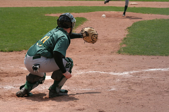 A catcher coming out his crouch to catch the pitch.