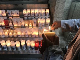mujer encendiendo velas de una ofrenda - obrazy, fototapety, plakaty