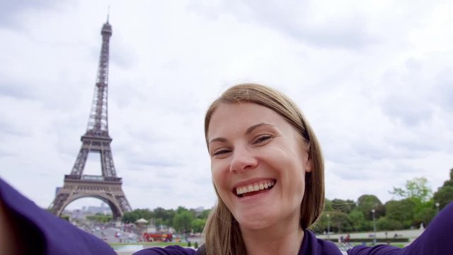 Woman near Eiffel Tower in Paris, France doing selfie on mobile phone. Happy smiling tourist woman traveling in Europe.