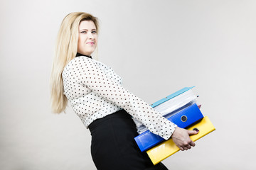 Woman holding heavy colorful binders with documents