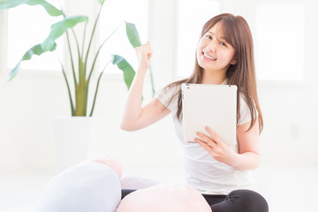 部屋でタブレットを見る女性