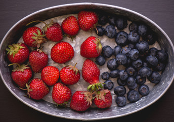 Blueberries and strawberries in galvanized steel container