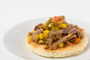Traditional Colombian arepa topped with shredded beef