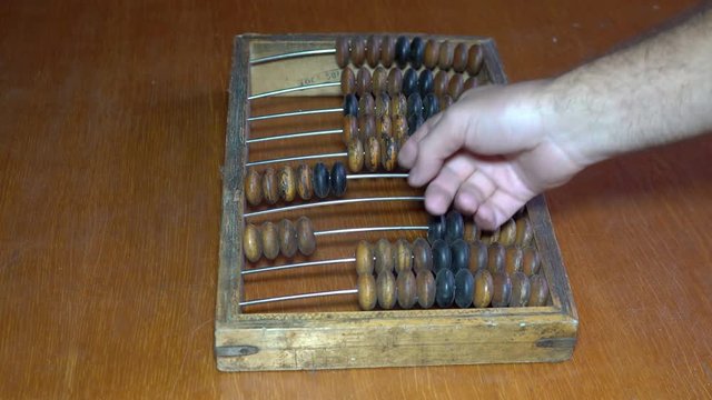Old wooden abacus. A person does a mathematical or accounting calculation.