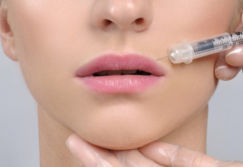 Close-up woman receiving filler injection in lips
