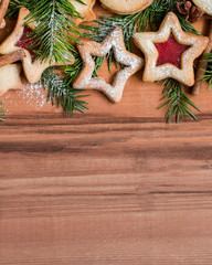 Ginger homemade cookies with strawberry jam on wooden background with Christmas tree. View with copy space. Flat lay, top view. Christmas Border - horizontal banner. Web size. stars.