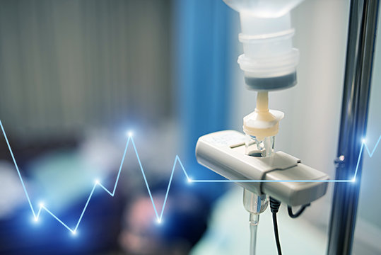 Close up saline solution drip for patient and infusion pump in hospital with heart rate graphic, Treatment of the disease of the doctor concept.