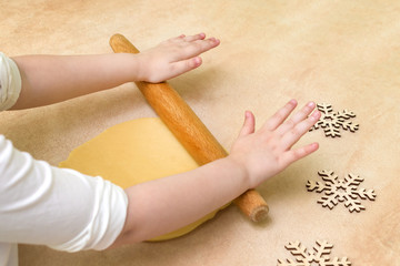 Child's hands sheeting dough with rolling pin