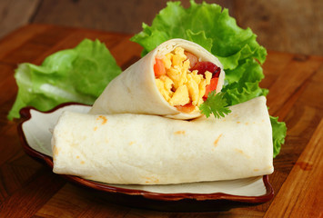 Burritos wraps with omelet ham and vegetables.