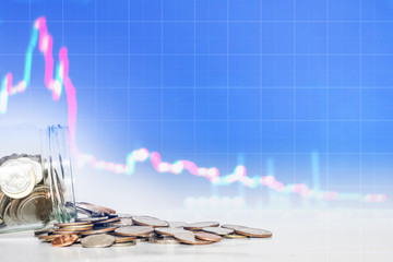 Coins spilled from glass jar with falling down graph background. lose money, bankruptcy and failure...