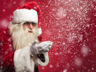 santa claus is blowing snow flakes out of his palms