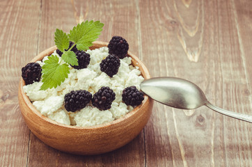 cottage cheese with blackberry in a wooden plate/cottage cheese with blackberry in a wooden plate. selective focus. Toned